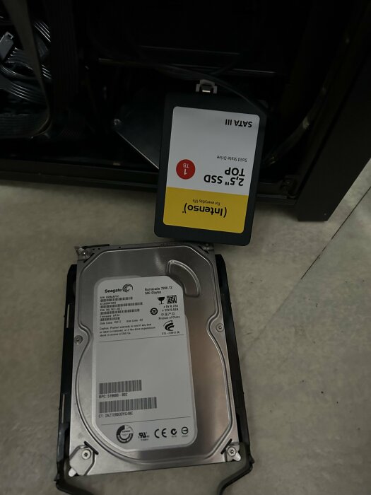 En SSD och en hårddisk ligger bredvid en dator, båda losskopplade, synliga märken är "Intenso" och "Seagate".