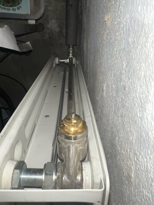 Bild av en radiatorventil monterad utan strypare, sett från sidan i ett rum med betongvägg.