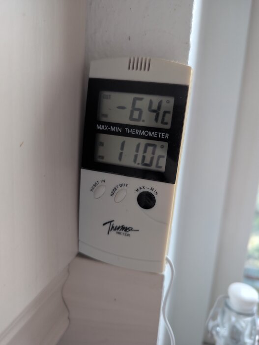 Termometer visar -6,4°C utetemperatur och 11,0°C inomhustemperatur monterad på vägg.