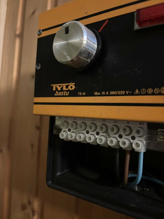 Kontrollpanel på Tylo bastu med vridknapp och kabelanslutningar med bokstäver istället för nummer.