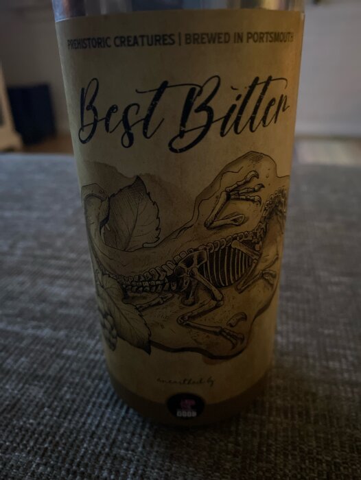 Etikett av ölflaska "Best Bitter" med illustration av ett skelett och texten "Prehistoric Creatures Brewed in Portsmouth".