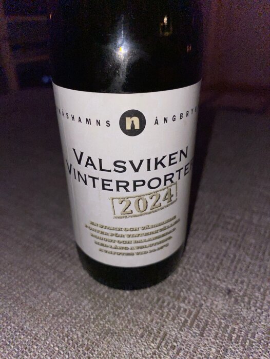 Flaska med Valsvikens Vinterporter 2024 från Nynäshamns Ångbryggeri på ett bord.