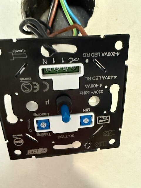 Närbild av en installerad dimmer med synliga kablar och knappar.