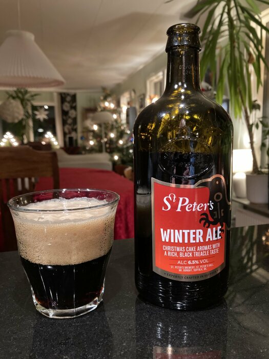 Flaska St Peter's Winter Ale och ett glas med julöl på ett bord, bakgrund av juldekorationer.