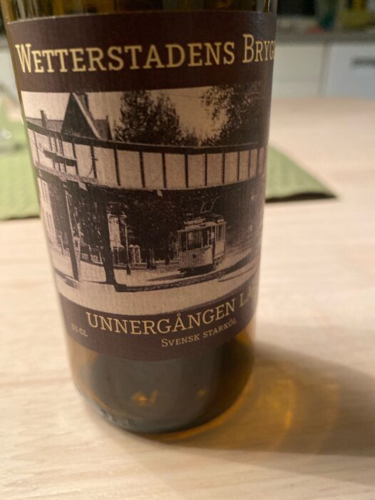 Flaska med etikett från Wetterstadens Bryggeri, Unnergången Lager, svensk starköl på bord.