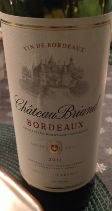 Flaska med Château Briand Bordeaux, årgång 2011, på ett bord.