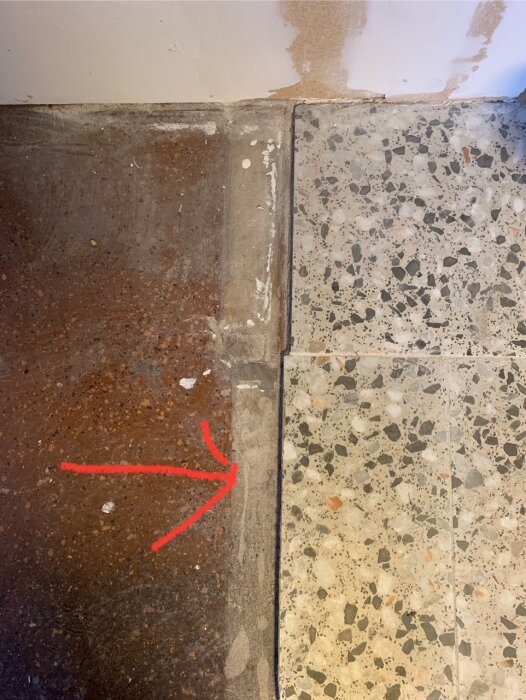 Närbild av klinkergolv där en röd pil markerar platsen där plattor behöver kapas i linje med överliggande platta.