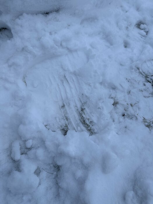 Fotavtryck i snön, visar två olika skosulor. Den vänstra sulan har tydliga mönster för grepp, medan den högra saknar detta tydligt.