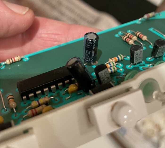 Kretskort nära bild med kondensatorer, två märkta 63V 10 mikrofarad, en markerad i blå ring och en kondensator märkt 1000 mikrofarad 16V i röd ring.