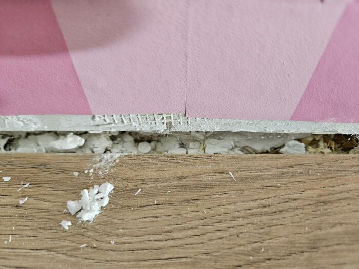 Poröst vitt material i vägg från 1960-talshus, exponerat vid borttagna lister, konstant oro om asbest eller gips, sovrumsrenovering.