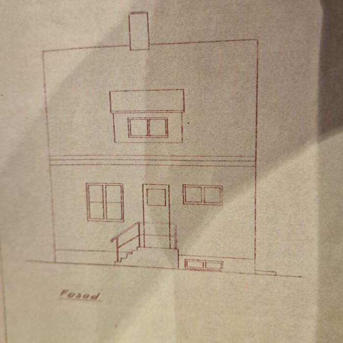 Arkitektritning av ett hus med två våningar, fönster och en dörr med trappa. Släta fasader, märkt "Fasad" i nedre kanten av ritningen.