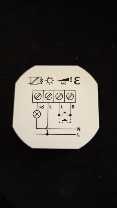 Kopplingsschema för UDN100 dimmer med symboler för taklampa och ledningar samt märkning av olika anslutningar.
