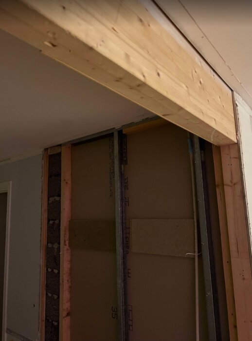 Bilden visar en inre vägg under renovering med synliga leca block och träreglar, och en bärande träbalk ovanför.