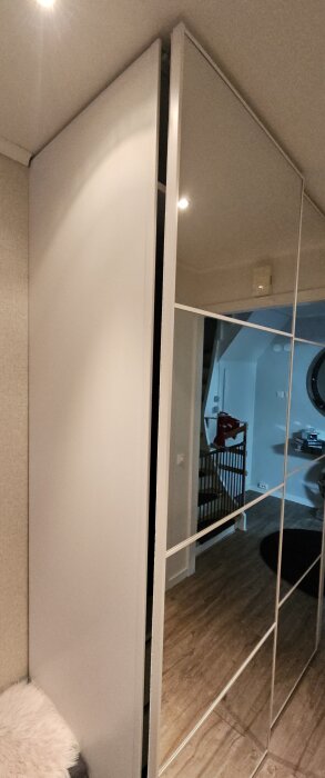 Glipa mellan skjutdörr och stomme på en Ikea Pax garderob, spegeldörr synlig, interiör av ett hus.