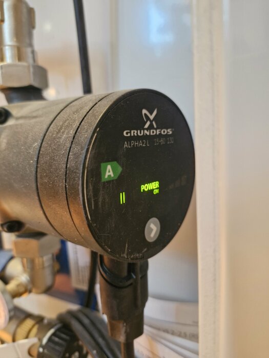 Närbild på en Grundfos ALPHA2L 15-60 130 cirkulationspump med grönt ljus som indikerar "Power On".