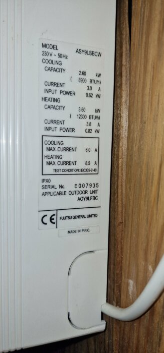 Etikett på Fujitsu luftvärmepump ASY9LSBCW med specifikationer för spänning, kapacitet, strömförbrukning och serienummer E007935.