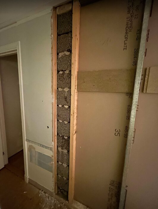 Vägg med synlig spalt av lecablock inomhus, delvis borttagen för renovering, antydan till konstruktion under öppen spis på övervåningen.