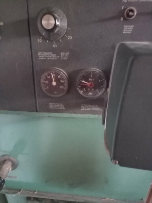 Manöverpanel med temperatur- och tryckjärnvisare visar pannans status. Regleringsknapp för temperatur synlig.