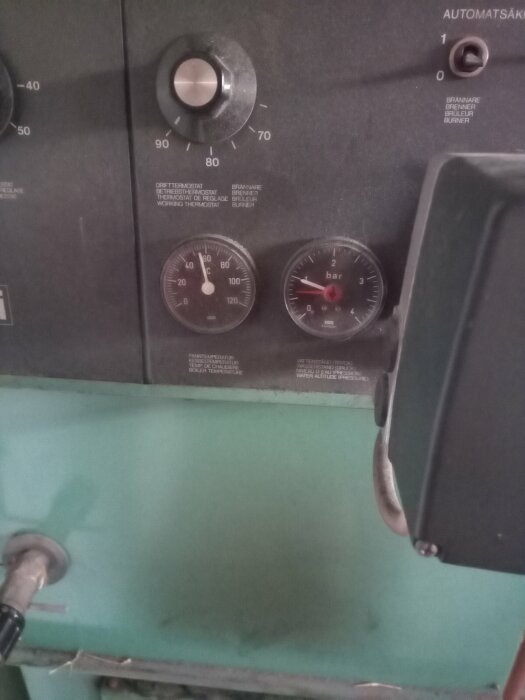 Panel med termostat, tryckmätare och temperaturmätare, del av en brännare eller pannanläggning. Knapp för automatisk säkring till vänster om mätarna.