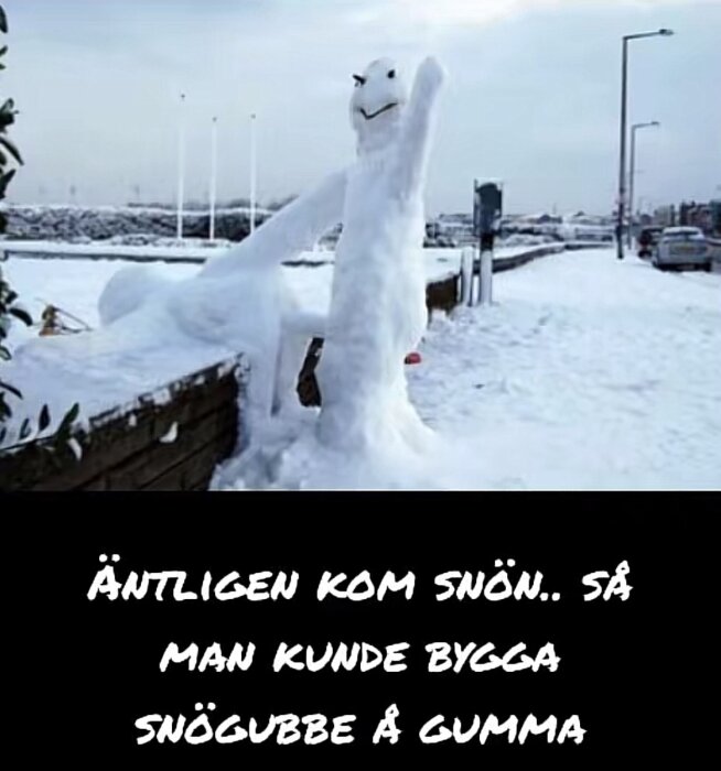 Två kreativa snöfigurer uppställda vid en trottoar; en står upp medan den andra ligger över en mur i vintermiljö.