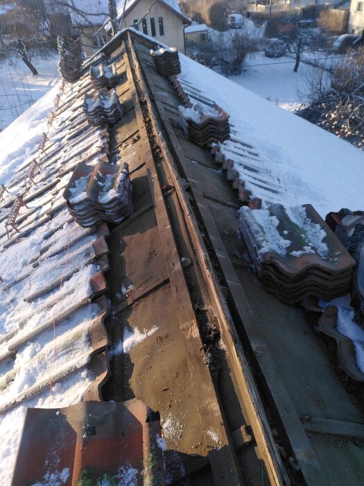 Snötäckt tak med staplade takpannor, förberedelser inför takhöjning.