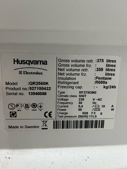 Etikett på Husqvarna kylskåp med tekniska specifikationer såsom modell QR2560K, volym och spänning. Made in Sweden.