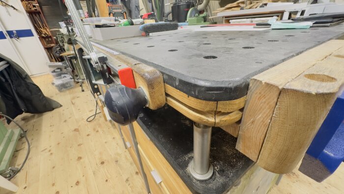 Workbench with integrated T-tracks and clamps, in a woodworking shop setup with tools and AEG router visible in the background.