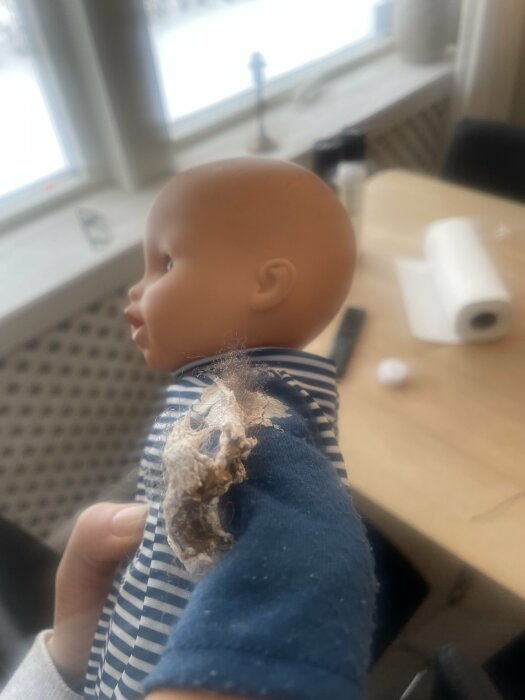 Närbild på en docka med hårt, gipsliknande vitmögel med svarta strån på ärmen. Personen undrar över förekomsten av vitmögel.