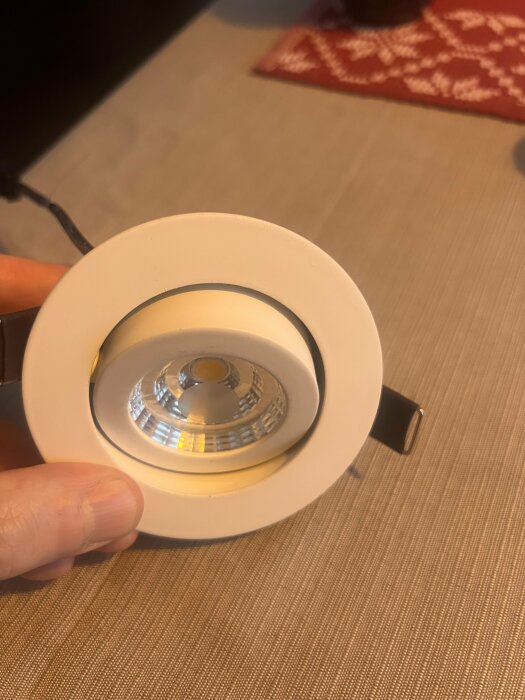 Downlight-insats från A-collection visas på närbild, hålls i handen. Fokus på ljuskällans hölje och reflektor, utan synlig lampa installerad.