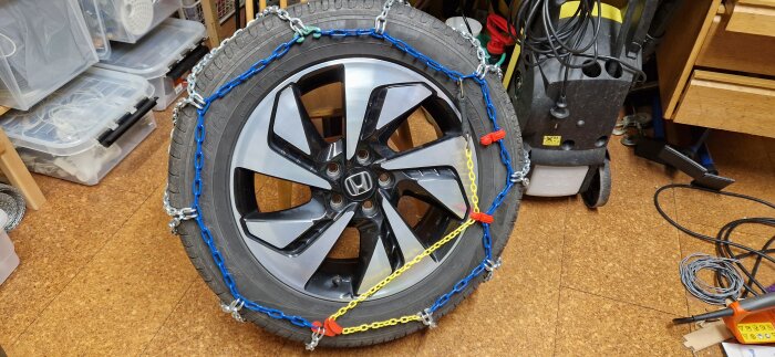 Bilens sommardäck med snökedjor monterade; i fokus är Biltemas snökedja SUV M på ett 225/60R18 däck på en Honda CR-V.