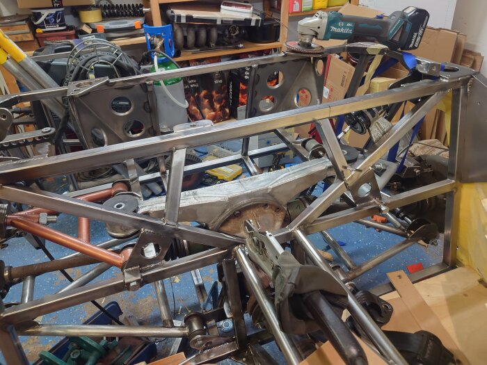 Metallram med bältesfäste och förstärkningsrör i ett garage. Verktyg och utrustning syns i bakgrunden.