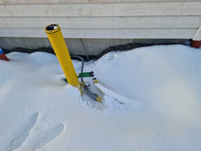 Gul slang med övergång till flexslang i snötäckt miljö, installation för solceller till växelriktare.