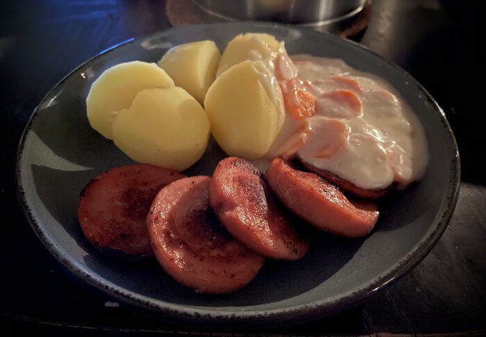 Tallrik med stekt falukorv, kokt potatis och stuvade morötter till middag.