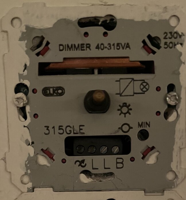 Trasig dimmer med märkning "DIMMER 40-315VA", 230V, 50Hz, och beteckningen "315GLE", monterad på vägg.