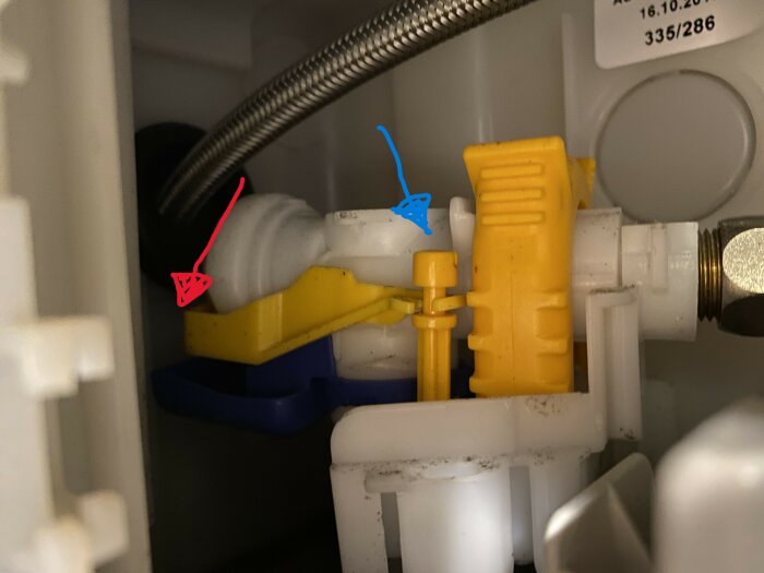 Närbild av flottören inuti en spolcistern, med en blå pil markerande flottören och en röd pil vid en vit del.