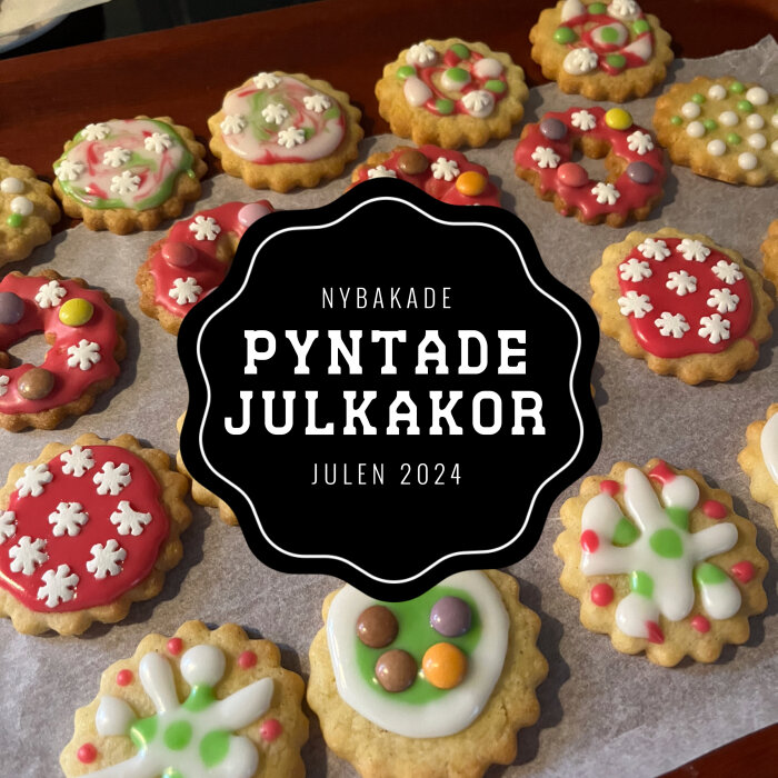 Nybakade och dekorerade julkakor med färgglad glasyr och strössel på ett bakplåtspapper, med text "PYNTADE JULKAKOR Julen 2024".