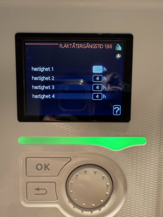 Display på värmepump med inställningar för fläkttider vid olika hastigheter, alla inställda på 4 timmar. Knapp och ratt för justering syns.