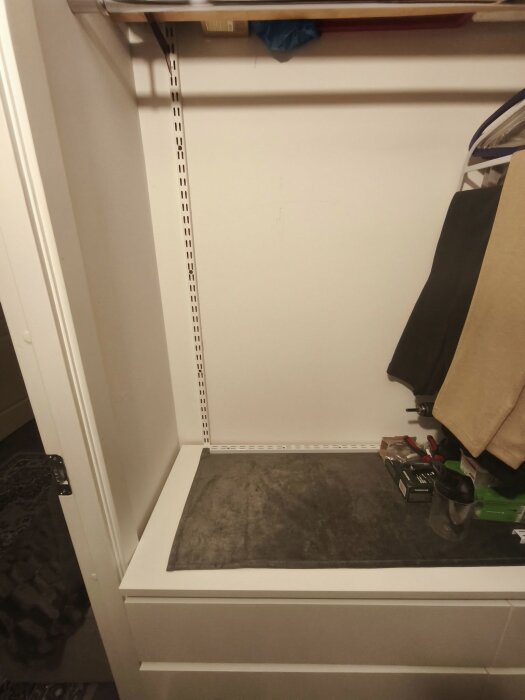 Ett tomt utrymme med en hyllskena på väggen avsett för montering av 3–4 hyllor för klädförvaring. Utrymmet är 1 meter brett och 70 cm högt.