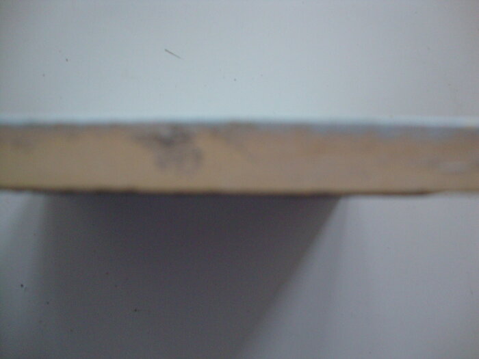 Närbild på kanten av en Ekeby kakelplatta med en diffus färg och textur, eventuellt annan nyans än förväntat.