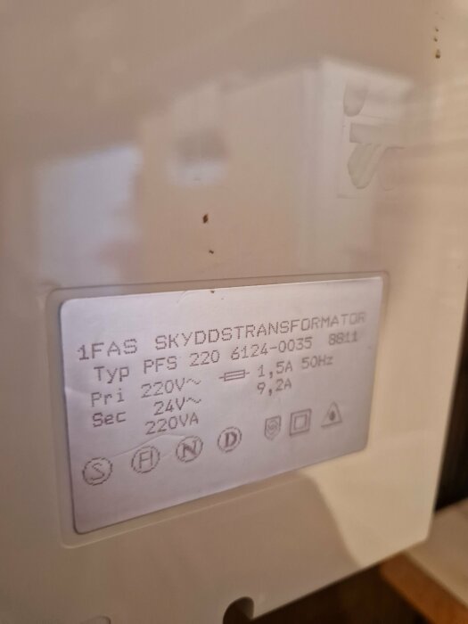 Vit transformator med etikett som visar specifikationer: 1-fas skyddstransformator, typ PFS 220, primär 220V, sekundär 24V, 220VA.