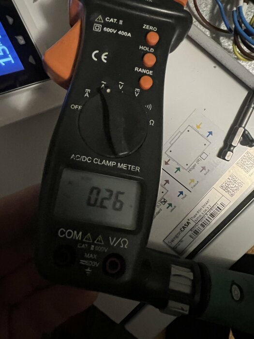 Multimeter visar 0,26A i strömintag. Bakgrund med kablar och Swegon-logotyp.