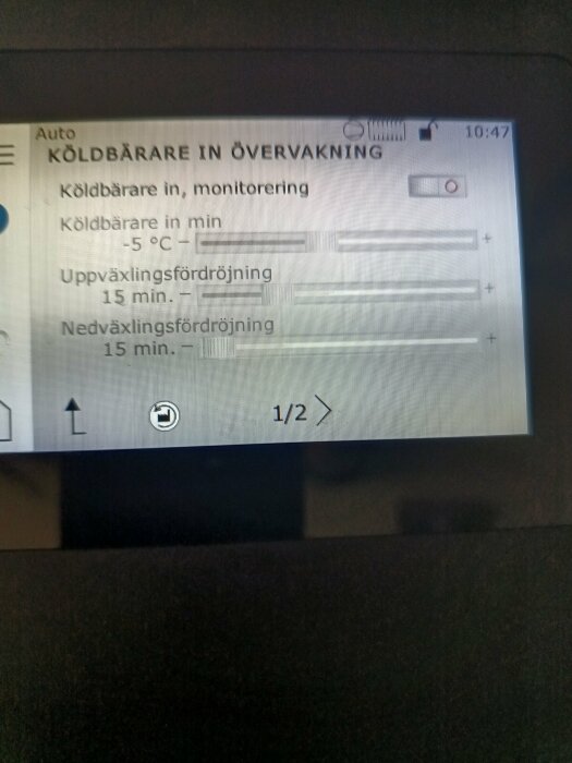 Närbild på en övervakningsskärm som visar inställningar för köldbärare med temperatur -5°C och tidsfördröjningar för upp- och nedväxling på 15 minuter.