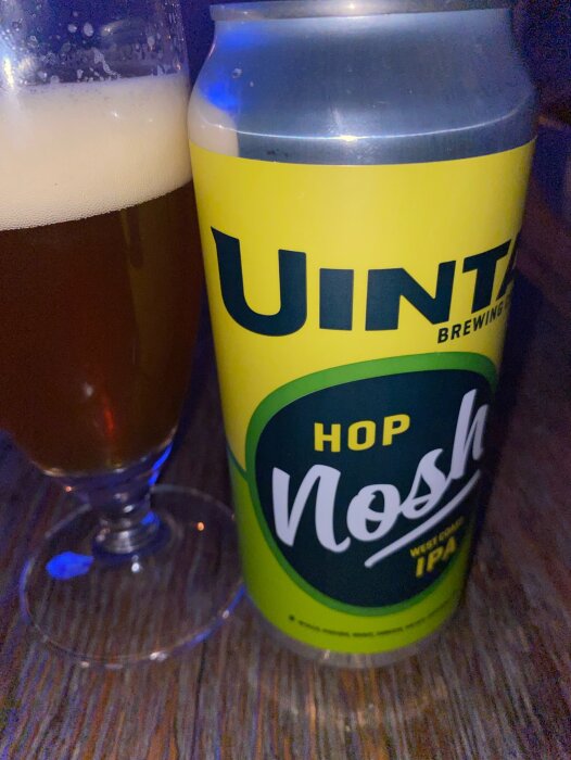 Burk med Uinta Brewing Hop Nosh IPA och ett glas öl på ett träbord.