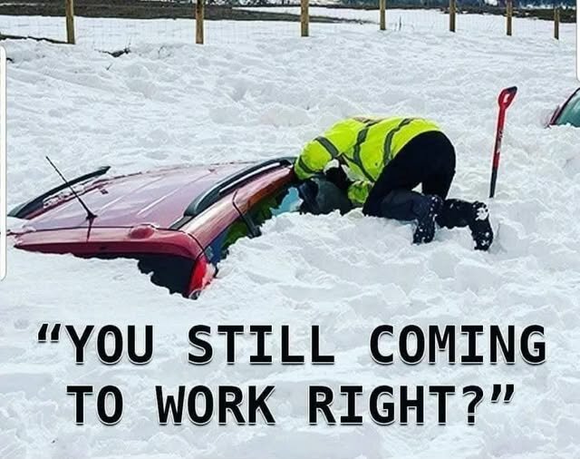 En person i varseljacka skottar snö från en delvis täckt bil, med texten "YOU STILL COMING TO WORK RIGHT?" i förgrunden.