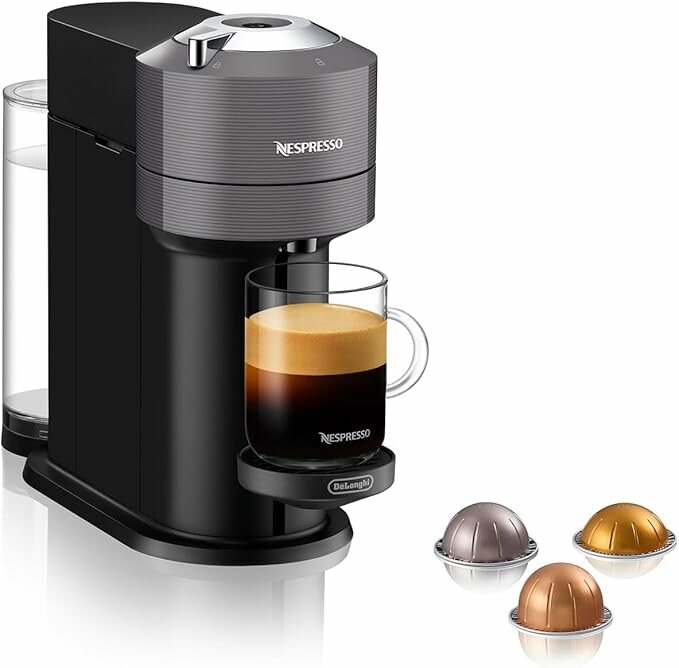 Nespresso kaffemaskin med kopp fylld av kaffe med tjockt skumlager, samt tre kaffekapslar i olika färger bredvid.