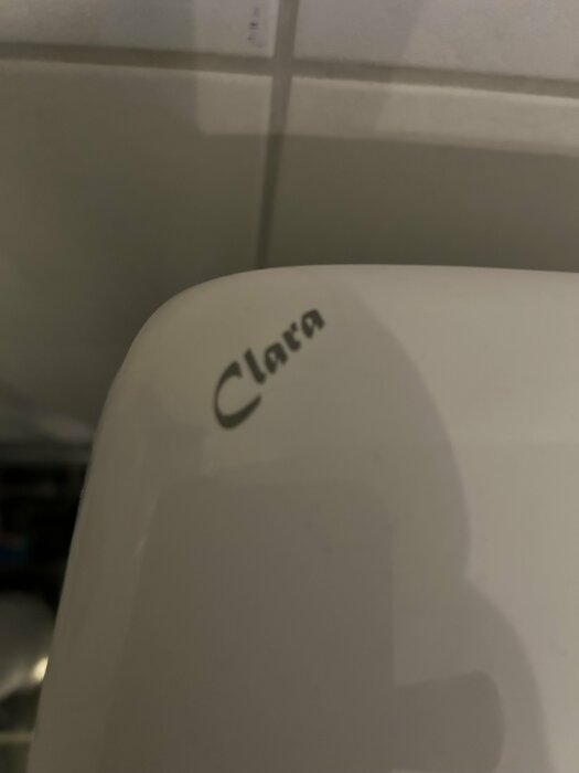 Närbild av en toalettcistern med texten "Clara" på locket.