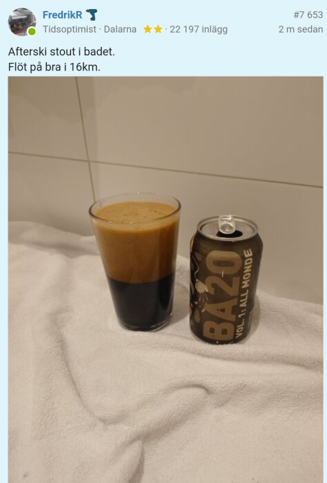 Ett glas med skummande stout och en burk märkt "BA20" står på en vit handduk i ett badrum.