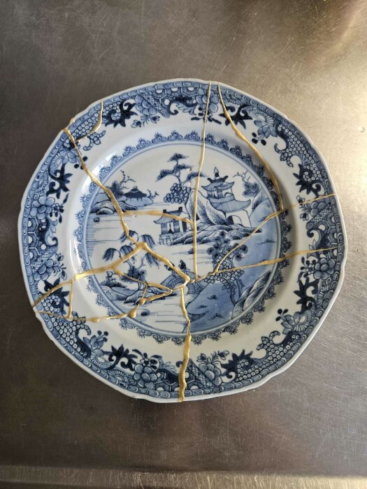 Kintsugi-talrik med sprickor reparerade med guldfärg.