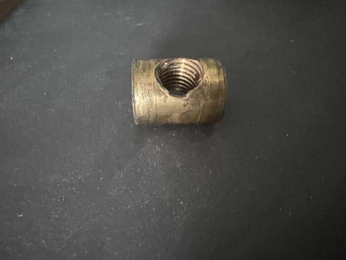 Trasig metallmutter med m12 gänga och 20 mm diameter, placerad på en svart yta.