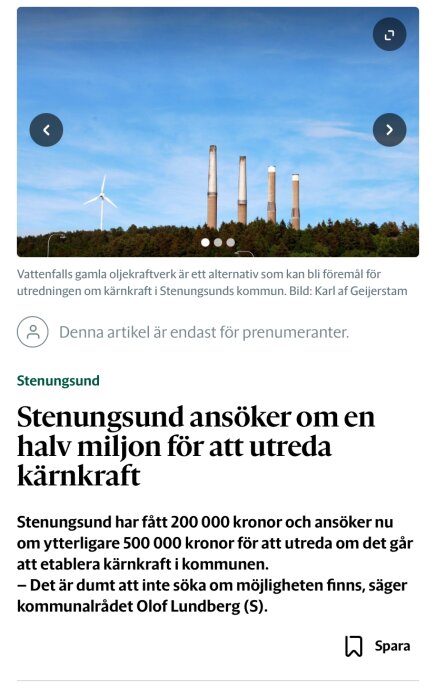 Kraftverk med tre skorstenar och ett vindkraftverk i förgrunden mot en blå himmel.